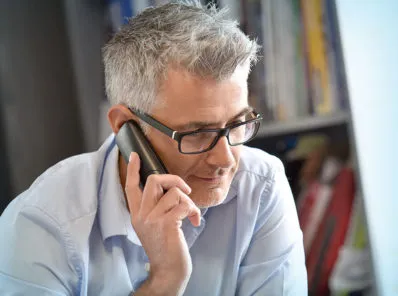 grey haired man talking on the phone