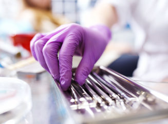 gloved hand reaching for dental tools